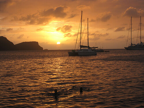 Sonnenuntergang mit Insel und Segelboot im Hintergrund